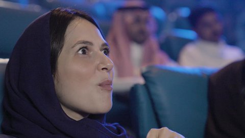 حضور العروض المسرحية والسينمائية، ايماءات الاندماج و الدهشه، تناول الفشار أثناء مشاهدة العروض، تصوير مقرب لامراة عربيه خليجيه سعودية تجلس في صالة السينما، قضاء أوقات ممتعة، أنشطه ترفيهيه