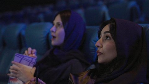 الاستمتاع بمشاهدة الأفلام في قاعات السينما،  ايماءات الاندماج و الدهشه،تناول الفشار أثناء مشاهدة العروض، تصوير مقرب صديقتان عربيتان خليجيتان يرتديان الحجاب يجلسان في صالة السينما، قضاء أوقات ممتعة،، مشاركة الفشار، الفشار وأفلام السينما، أنشطه ترفيهيه