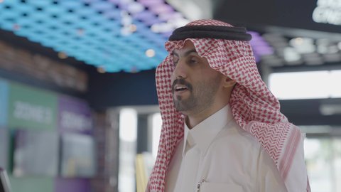 التحضير لدخول قاعة السينما، تصوير مقرب لرجل سعودي يرتدي الزي التقليدي والشماغ يقوم بشراء سناكس المأكولات والمشروبات في ردهة الإستقبال داخل السينما، مشاهدة الأفلام والعروض المسرحية، سينما ومسرح، أنشطه ترفيهيه