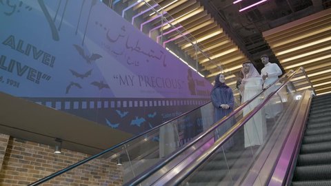 التجول والصعود عبر السلالم والأدراج الكهربائيه, مجموعه من الاصدقاء العرب الخليجين السعوديين  يرتدون الزي التقليدي يقومون باستخدام الدرج الكهربائي, متعه التسوق والشراء في المولات السعوديه, الاستمتاع في قضاء وقت ممتع مع العائله, شراء المستلزمات والهدايا