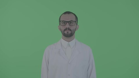 الاهتمام بالطب و الرعاية الصحية، الاستعداد التام لتقديم الخدمات الطبيه، بورتريه طبيب عربي خليجي سعودي يرتدي المعطف الابيض باستقامة بايماءات الثقة والاستعداد، النظر الى شيء ما ، خلفية خضراء ، كروما