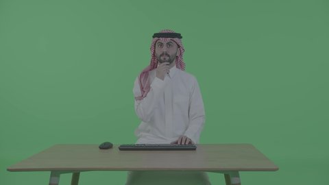 صناعة المحتويات النصية، مفهوم ادخال البيانات، دمج التكنولوجيا الحديثة بالحياة العملية، مهن ووظائف إدارية مكتبية، بورترية لرجل عربي خليجي سعودي يرتدي الزي التقليدي و الشماغ يجلس على الطاوله يقوم بالنقر على لوحة المفاتيح، ، ايماءات التفكير فى شيء ما ، خلفية خضراء ، كروما