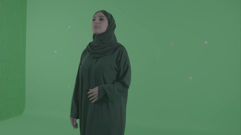 تحريك العناصر الرقمية باللمس على واجهة الشاشة، امراة عربيه خليجيه سعودية تقوم بالرسم والتخطيط في الهواء، محاكاة العالم الخيالي، خلفية خضراء ، كروما