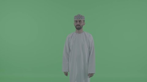 Simulation of a fantasy world, tapping expressions on a screen, using the sense of touch to move an element, an Arab Gulf Omani man wearing a dishdasha and a kumma drawing and planning in the air, green background, chroma.