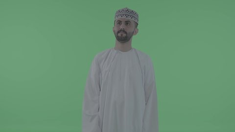 Expressions of tapping on a screen, using the sense of touch to move an element, an Arab Gulf Omani man wearing a dishdasha and kumma drawing and planning in the air, simulating a fantasy world, green background, chroma.