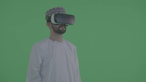التطور التكنولوجي والفني، المتعة والترفيه من خلال المشاهدة عبر نظارات الواقع الافتراضي، صورة لشاب عماني خليجي يرتدي الدشداشة والكمّة ونظارات ثلاثية الأبعاد، الانغماس والمحاكاة للعالم الخيالي، خلفية خضراء، كروما