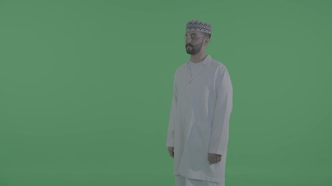 Click and drag to move the contents of the virtual screen, a side shot of an Arab Gulf Omani man wearing a dishdasha and kumma drawing and planning in the air, simulating a fantasy world, green background, chroma.