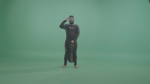 Preparing for an adventure of diving into the depths of the sea, the concept of marine and recreational activities, a portrait of an Arab Gulf Saudi man wearing a diving suit and swimming goggles, full-body, green background, chroma.