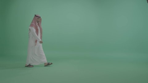 ايماءات المشي و الذهاب إلى مكان معين، الاهتمام بالمظهر الخارجي، مفهوم الأناقة والرجولة والقوة، بورتريه لرجل عربي خليجي سعودي يرتدي الزي التقليدي و الشماغ   ينظر إلى الكاميرا بتعابير السرور والسعادة، التقدم إلى الأمام بخطوات ثابتة، الجسم بالطول الكامل ، خلفية خضراء ، كروما