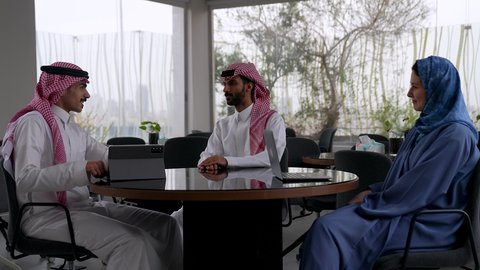 فريق عمل سعودي  في غرفة الإجتماعات داخل مقر الشركة، إستخدام جهازالتابلت، مهن ووظائف سعودية،الشراكة في الأعمال والمشاريع، عقد صفقات عمل جديدة ناجحة بين رجال الأعمال، رجلان سعوديان يقومان بمصافحة بعضهما، ايماءات السعادة و السرور
