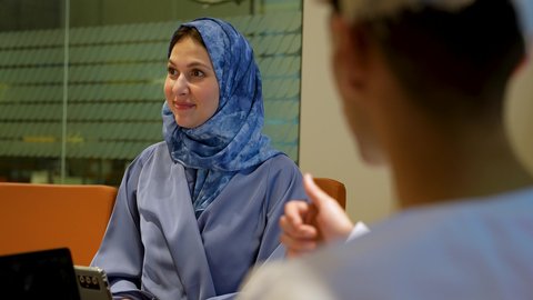 التركيز والعمل الجاد، مناقشة الخطوات القادمة، تصوير مقرب لامراة عربيه خليجيه عمانية محجبة ترتدي العباءة تجلس داخل غرف الاجتماعات  تقوم  بإبداء الرأي ومشاركة الأفكار، الحوارات والنقاشات ضمن الفريق، ضمان فهم واضح للاعمال، الاحترافية في الإنجاز