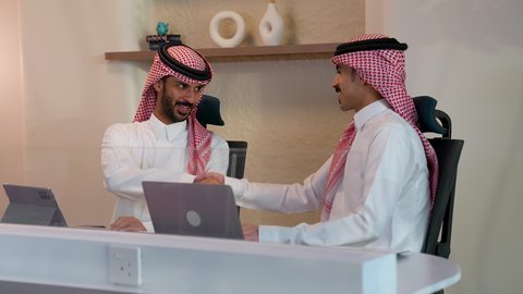 العمل في الشركات الخليجية الراقية, التحية والسلام والاتفاق على صفقات عمل ناجحة, رجلا أعمال عربيان خليجيان سعوديان يرتديان الثوب التقليدي والشماغ يقومان بالمصافحة بتعابير السرور, مهن ووظائف سعودية