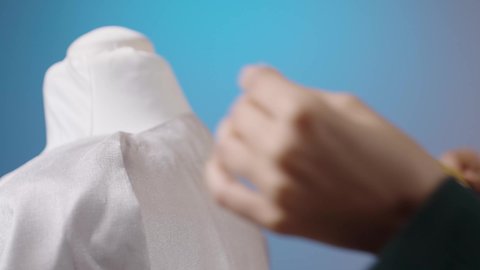 ابتكار وتصميم ملابس للمرأة، مهن و أعمال الخياطة و التصميم, بورتريه مقرب ليد مصممه أزياء عربية خليجية سعودية تقف أمام المانيكان تأخذ القياسات بالشريط المتري , خلفية ملونه