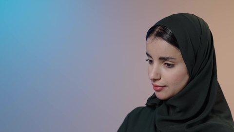 مستلزمات التفصيل والخياطة، مهن و أعمال الخياطة و التصميم , تفصيل الملابس النسائية , بورتريه مقرب لمصممة أزياء عربية خليجية سعودية ترتدي العباءة السوداء والحجاب تقف أمام المانيكان تأخذ القياسات بالشريط المتري , خلفية ملونه