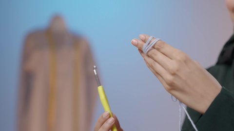 ممارسة مهنة الخياطة، تصوير مقرب ليد امرأة عربية خليجية سعودية محجبه ترتدي العباءة تستخدم إبرة الكروشيه وخيوط الصوف ، أعمال تقليدية شعبية, فنون الخياطة و التصميم , الإبداع في ابتكار موديلات جديدة