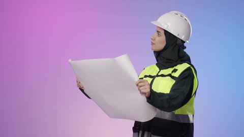 Monitoring the implementation of engineering works, architectural construction plans, the development and progress of Saudi Arabia by the hands of the nation's sons, a portrait of a smiling Arab Gulf Saudi engineer wearing a helmet and safety vest holding a plan in her hand looking at something.