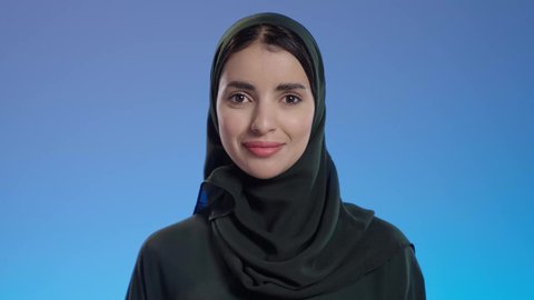 الاستمتاع بالتبضع فى السعودية، التسوق في المراكز التجاريه، بورتريه مقرب لإمرأة عربيه خليجية سعوديه محجبة ترتدي عباءه سوداء تحمل بيدها أكياس التسوق, عروض وتخفيضات موسميه, إيماءات تدل على السعاده، خلفية ملونه