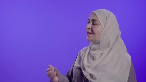 Feeling lazy and lethargic, feeling tired and in need of rest, a photograph of an elderly Saudi Arabian Gulf woman wearing an abaya and hijab, putting her hands over her mouth in a sleepy gesture, expressions of drowsiness and exhaustion.
