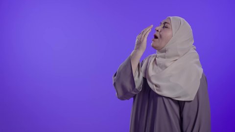 Feeling tired and in need of rest, feeling lazy and lethargic, a photograph of an elderly Saudi Arabian Gulf woman wearing an abaya and hijab, putting her hands over her mouth in a sleepy gesture, expressions of sleepiness and exhaustion.