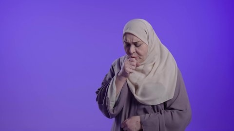 الانفلونزا والتهاب الرئه،الشعور بالمرض والكحة،  تصوير لامراه عربيه خليجيه سعوديه كبيره بالسن ترتدي العباءه والحجاب  تعاني من السعال،  الاصابة بفايروس كورونا