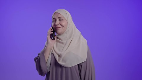 اجراء مكالمه هاتفيه ،الدردشة والتحدث مع الأصدقاء، النظر إلى الهاتف المحمول بإيماءات الاندماج،  تصفح مواقع وتطبيقات الانترنت،  تصوير لامراه عربيه خليجيه سعوديه كبيره بالسن ترتدي العباءه والحجاب تمسك الجوال بيدها، استخدام التقنيات والتكنولوجيا الحديثة بالحياة اليومية