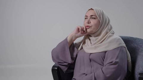 محاولة إيجاد حل لمشكلة ما, التمعن والتركيز والتخطيط للمستقبل ، إيماءات الحيرة والقلق, النظر بشرود إلى مكان ما, تصوير لامراه عربيه خليجيه سعوديه كبيره بالسن ترتدي العباءه والحجاب تجلس على كرسي ، تنظر بعيداً بتعابير التفكير والتأمل