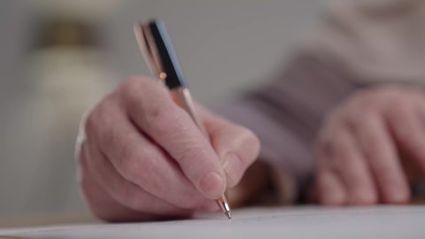 Business administration and organization, using blank paper at work, taking notes and recording information on paper, close-up of an elderly Saudi Arabian Gulf woman wearing an abaya and hijab sitting at a desk, writing down daily tasks and goals.