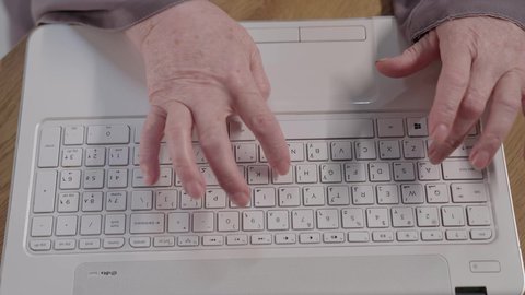 Close-up of an elderly Saudi Arabian Gulf woman wearing an abaya and hijab sitting at a desk working on a laptop, integrating advanced technology into daily life, using modern technologies in administrative work, employment in Kuwaiti offices and companies, focus, dedication and hard work
