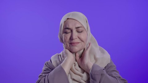 الحاجة للعلاج والذهاب للطبيب,  الإحساس بوجع في الرقبة،التألم والشعور بالتعب والإرهاق, آلام العظام والمفاصل, تصوير لامراه عربيه خليجيه سعوديه كبيره بالسن ترتدي العباءه والحجاب تضع يديها على عنقها بتعابير الألم
