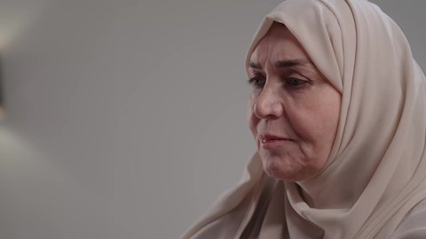 Recruitment in Kuwaiti offices and companies, focus, dedication and hard work, close-up of an elderly Saudi Arabian Gulf woman wearing an abaya and hijab sitting at a desk and working on a laptop, use of modern technologies in administrative work, integration of advanced technology into daily life