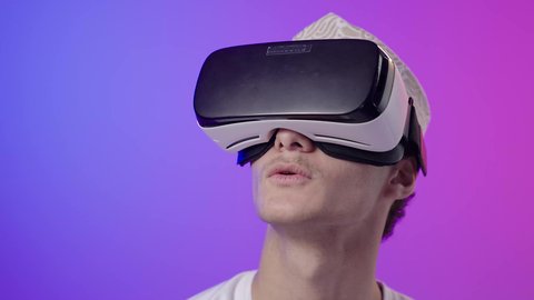 ايماءات الاندماج و الدهشه، المتعة بالمشاهدة عبر نظارة الواقع الافتراضي، بورتريه مقرب لولد عربي خليجي عماني يرتدي الدشداشه والكمه ينظر من خلال نظارات ثلاثية الأبعاد (الفي ار)، محاكاة العالم الخيالي، استخدام جهاز تقني حديث ومتطور،خلفية ملونه