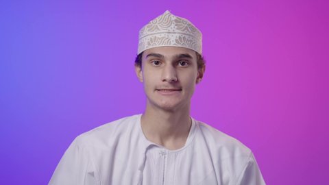 PlayStation entertainment games, a close-up portrait of an Omani Gulf Arab boy wearing a dishdasha and kumma sitting and holding a remote control in his hand, facial expressions indicating happiness and excitement, focus and immersion, technologies and games, video games, spending enjoyable times, colorful background.