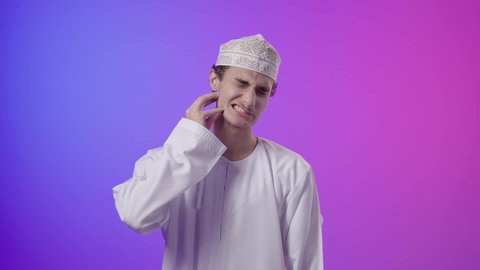 الاحتياج الى زيارة طبيب الأسنان، التهاب اللثه وتسوس الأَضراس، بورتريه لولد عربي  خليجي عماني يرتدي الدشداشة و الكمه يضع يده على خده بإيماءات تدل على ألم الأسنان,  التعب والإرهاق والحاجة لطلب العلاج والمساعده, خلفية ملونه