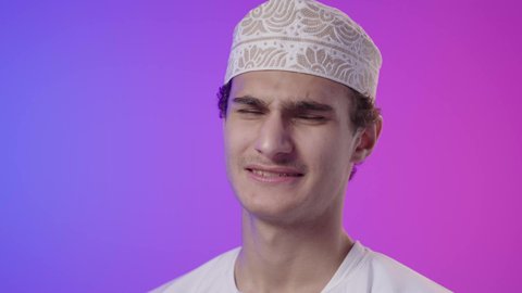 الأوجاع والآلام العصبية، طلب المساعده والحاجه للعلاج، التهاب العضلات والمفاصل، بورتريه مقرب لولد عربي خليجي عماني يرتدي الدشداشة و الكمه يضع يده على ظهره بايماءات الألم والتعب والأرهاق، خلفية ملونه