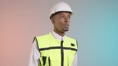 ادارة المشاريع الهندسية، مفهوم الهندسة الصناعية، الاشراف في موقع العمل، مهندس عربي خليجي سعودي يرتدي خوذة وسترة الحماية خاصة بالعمل يقوم بكتابة وتدوين الملاحظات, خلفيه ملونه