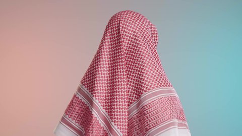 شاب عربي خليجي سعودي يرتدي الثوب والشماغ التقليدي مبتسم يقف بايدي متقاطعه, ملامح الفخر والاعتزاز, خلفيه ملونه