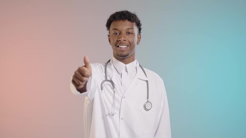 الاعجاب بنتائج ايجابيه, طبيب عربي خليجي سعودي يرتدي المعطف الابيض والسماعه الطبيه يشعر بالقبول والموافقه, خلفيه ملونه