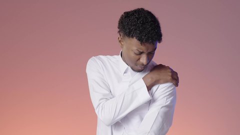 الإحساس بالمرض ووجع العظام والعضلات، طلب المساعده والحاجه للعلاج، الأوجاع والآلام العصبية والعضلية، شاب عربي خليجي سعودي يرتدي الثوب التقليدي يمسك بكتفه من شده الالم, الانزعاج من الم المفاصل, خلفيه ملونه