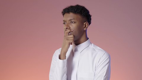 الحيره والتفكير في امر ما, بورتريه لشاب عربي خليجي سعودي يرتدي الثوب التقليدي يقف باستقامه يفكر ويضع يده علي وجهه, خلفيه ملونه