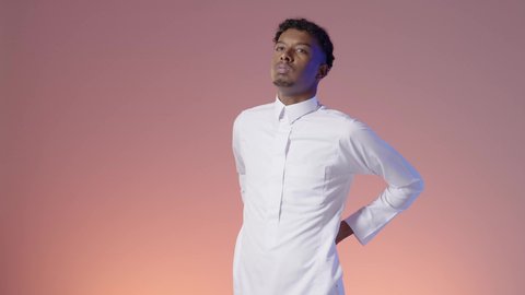 الحاجة إلى العلاج من آلام العامود الفقري والظهر، الشعور بالوجع والألم الجسدي، التعب والإرهاق والإحساس بالمرض، بورتريه لرجل عربي خليجي سعودي يرتدي الثوب التقليدي يضع يده على ظهره، خلفيه ملونه