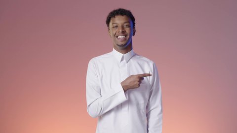 الاندهاش من امر ما، شاب عربي خليجي سعودي مبتسم يرتدي الثوب التقليدي يشير بإصبع السبابه، الوقوف بثقه في النفس، ايماءات الفرح والسرور، خلفيه ملونه