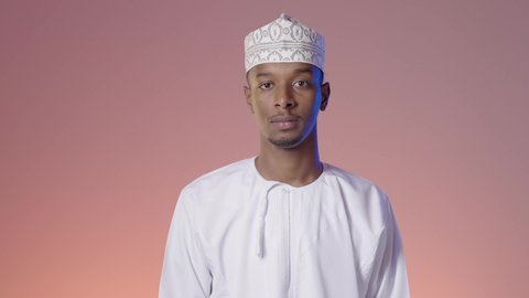 مفهوم الرجولة والثقة بالنفس، الوقوف باستعداد واستقامة، الاهتمام بالمظهر الخارجي والاناقة، رجل عربي خليجي عماني يرتدي الدشداشه والكمة يقف بإيماءات ايدي متقاطعة ينظر الى الكاميرا بتعابير الفرح والسرور