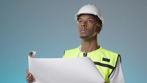 التركيز والاندماج في العمل, مهن ووظائف للشباب في السلطنة، مهندس عربي خليجي عماني يرتدي سترة عاكسة و خوذة بيضاء و يمسك بيديه مخطط المشروع