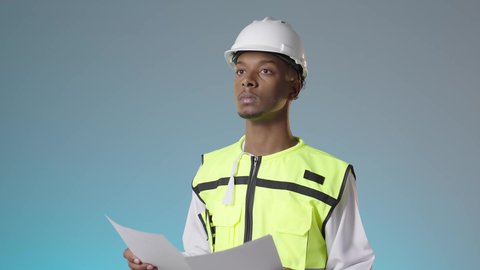 إدارة المشاريع الهندسية الإعمارية، مفهوم الانشاءات المعمارية، مهندس عربي خليجي عماني يرتدي سترة عاكسة و خوذة بيضاء و يمسك بيديه مخطط المشروع