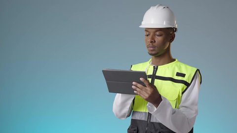 العمل في القطاع الهندسي، مفهوم إدارة المشاريع وتدقيقها، مهندس عربي خليجي عماني يرتدي سترة عاكسة و خوذة بيضاء يمسك بيديه تابلت، مهنة ووظيفة للشباب