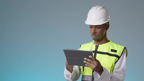 مراجعة مخطط المشروع ومتابعة الاعمال، العمل في القطاع الهندسي، مفهوم إدارة المشاريع وتدقيقها، مهندس عربي خليجي عماني يرتدي سترة عاكسة و خوذة بيضاء يمسك بيديه تابلت، مهنة ووظيفة للشباب