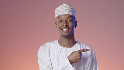 الإشارة والتوجيه الى مكان ما، رجل عربي خليجي عماني يرتدي الدشداشة والكمه يقف مبتسما ويشير باصبع السبابه الى مكان ما، تحديد موقع او هدف معين