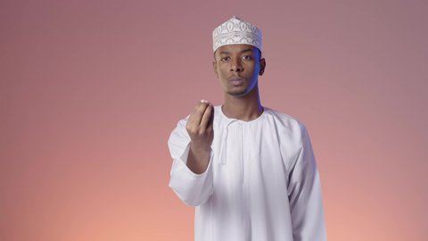 إمهال بعض الوقت للقيام بشئ ما، رجل عربي خليجي عماني يرتدي الدشداشة والكمه ينظر الى الكاميرا يشير بيده بإيماءات طلب الإنتظار, مفهوم الصبر والتريث