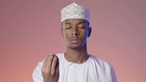 The concept of patience and deliberation, giving some time to do something, an Arab Gulf Omani man wearing a dishdasha and a kurta looking at the camera and making gestures asking to wait