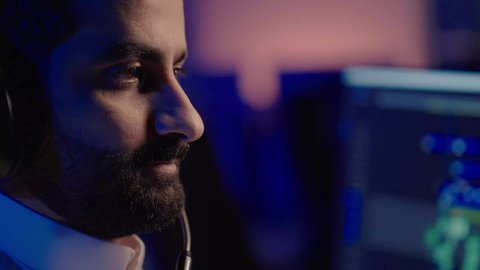 استخدام برامج تحرير متطورة لإنتاج الفيديوهات، إيماءات الانسجام مع المؤثرات الصوتية والمرئية، تصوير مقرب من الجانب لمونتير عربي خليجي سعودي يرتدي الثوب الابيض وسماعات الرأس يقوم  بالتأمل والإبداع الفني أمام الشاشة